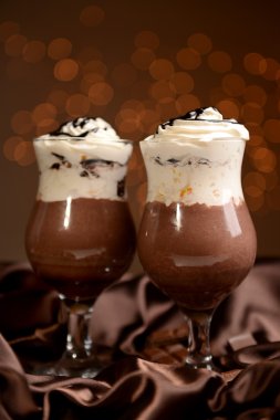 Işıklar arka plan üzerinde ahşap masa üstünde çikolata, krema ve portakal soslu lezzetli tatlı