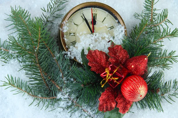 Reloj con ramas de abeto y decoraciones de Navidad bajo la nieve de cerca —  Fotos de Stock