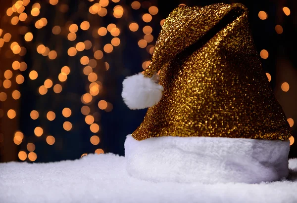 Sombrero de Santa sobre nieve sobre fondo de luces — Foto de Stock