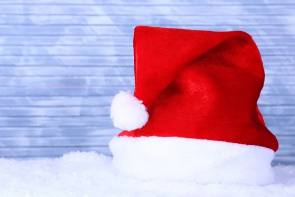 Santa hat on snow on color wooden background — Stock Photo, Image