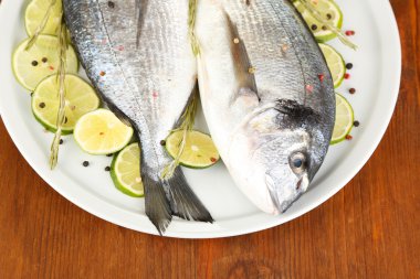 dorado ahşap masa yakın çekim plaka üzerinde limon ile iki balık