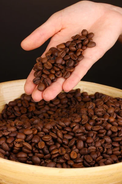 Koffiebonen in de hand op donkere achtergrond — Stockfoto