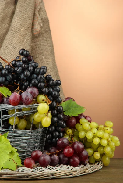 Assortiment van rijp zoete druiven in mand, op bruine achtergrond — Stockfoto