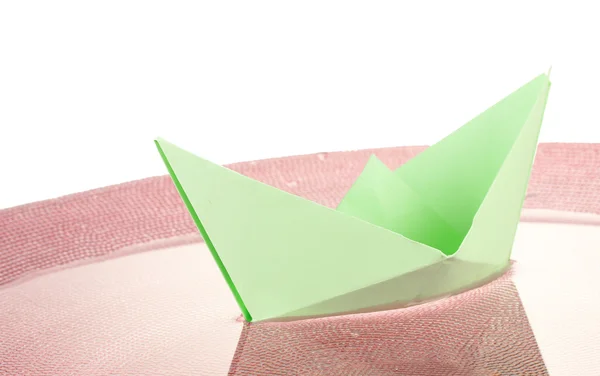 Barevný papír loď ve vodě na růžovém talíři, close-up — Stock fotografie