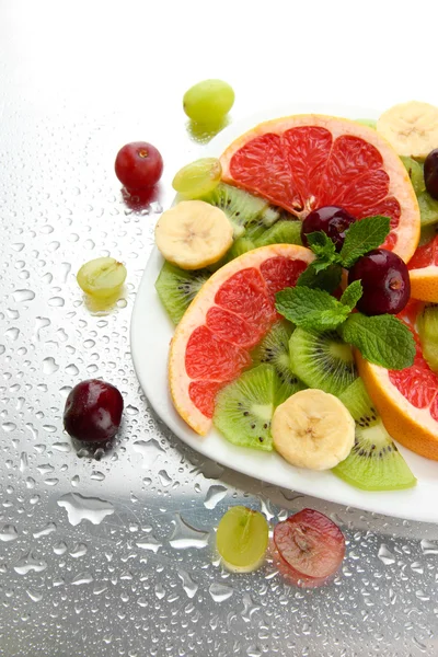 Assortment of sliced fruits on plate with drops — Stock Photo, Image