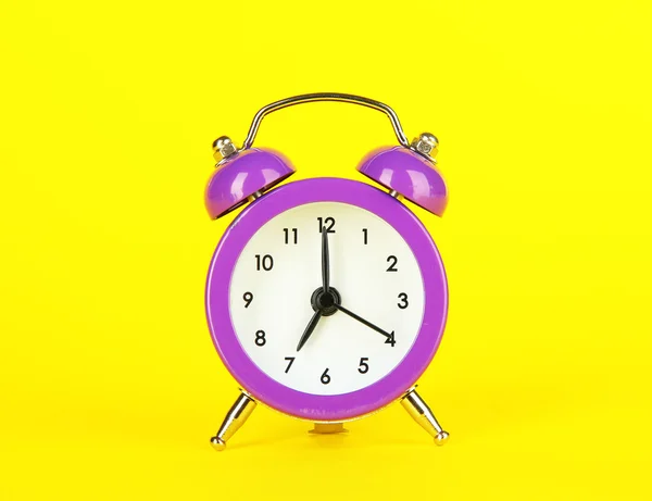 Purple alarm clock on yellow background — Stock Photo, Image