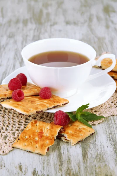 Kopje thee met koekjes en frambozen op tabel close-up — Stockfoto