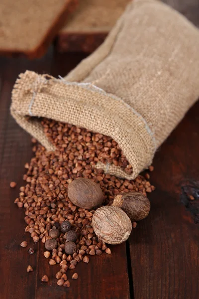 Cloth bag with buckwheat groats and spices on wooden background — Stock Photo, Image