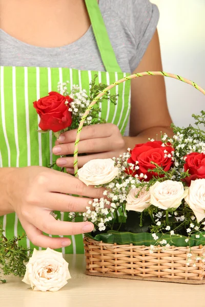 Florist makes flowers bouquet in wicker basket — Stock Photo, Image