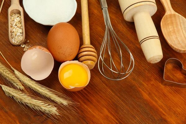 Vaření koncepce. základní pečící ingredience a kuchyňské nástroje na dřevěný stůl — Stock fotografie