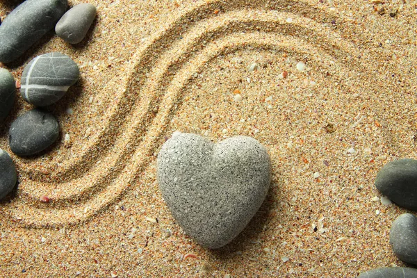 Grey zen stone in shape of heart, on sand background — Stock Photo, Image