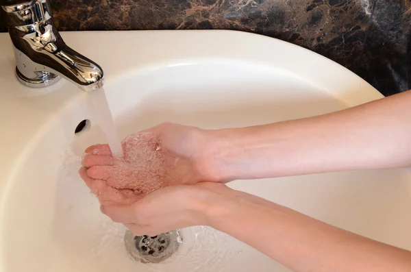 Nahaufnahme menschlicher Hände, die im Badezimmer unter dem Wasserhahn gewaschen werden — Stockfoto