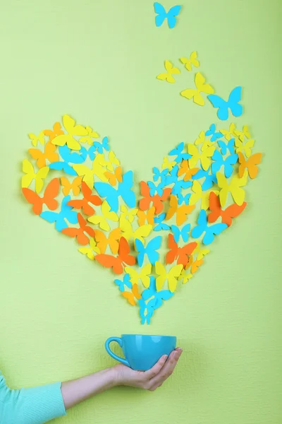 Paper butterflies fly out of cup on green wall background — Stock Photo, Image