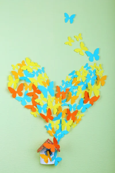 Paper butterflies fly out of nesting box on green wall background — Stock Photo, Image