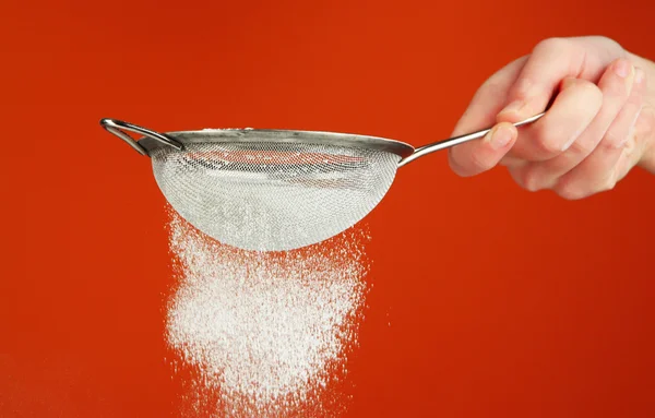 Sieve and powdered sugar on orange background — Stock Photo, Image