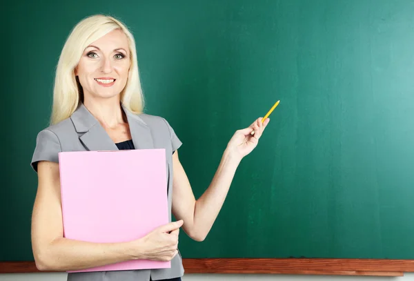 Schoolleraar met map in de buurt van blackboard close-up — Stockfoto