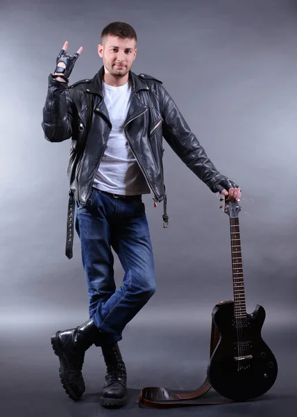Młody muzyk z gitarą na tle ciemnego koloru — Zdjęcie stockowe
