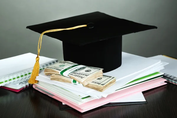 Dinero para graduación o entrenamiento en mesa de madera sobre fondo gris —  Fotos de Stock