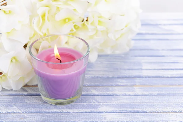 Schöne bunte Kerzen und Blumen, auf farbigem Holzhintergrund — Stockfoto