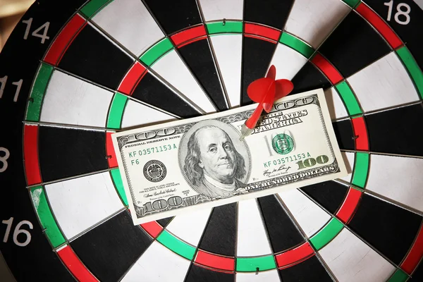 Money pierced by arrow on dartboard close up — Stock Photo, Image