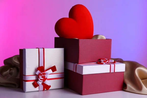 Stapel geschenkdozen en decoratieve hart, op een achtergrond met kleur — Stockfoto
