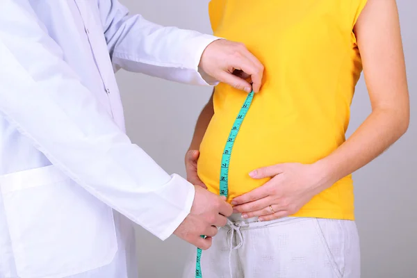 Jeune femme enceinte avec médecin sur fond gris — Photo