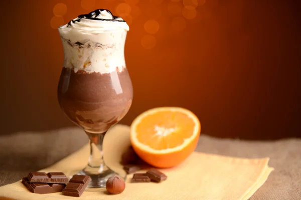 Gustoso dessert con cioccolato, crema e salsa d'arancia, su tavolo di legno, su sfondo luci — Foto Stock