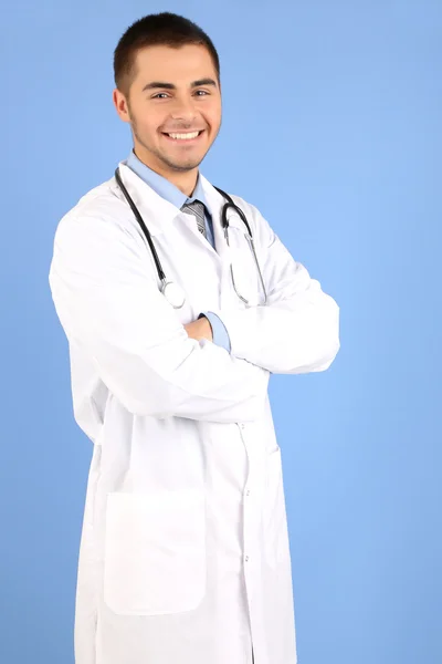 Médico masculino de pé com pasta, no fundo azul — Fotografia de Stock