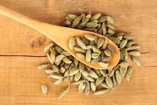 Green cardamom in wooden spoon on wooden background close-up — Stock Photo, Image