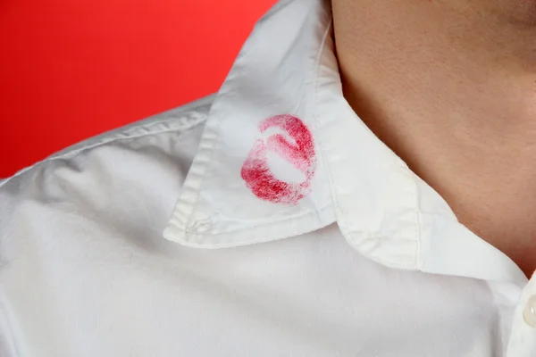 Beso de lápiz labial en el cuello de la camisa del hombre, sobre fondo rojo — Foto de Stock
