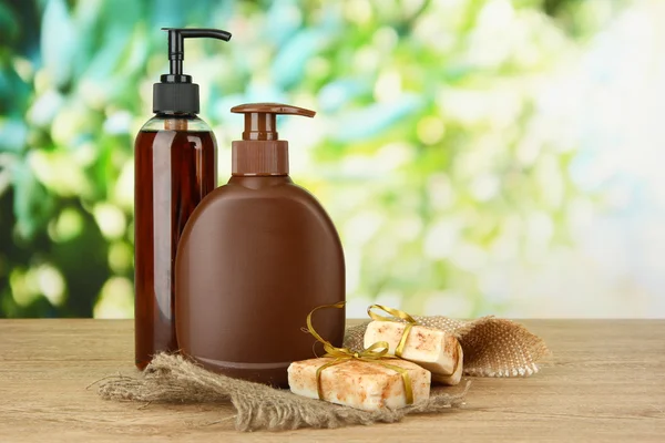 Liquid and hand-made soaps on wooden table, on green background — Stock Photo, Image