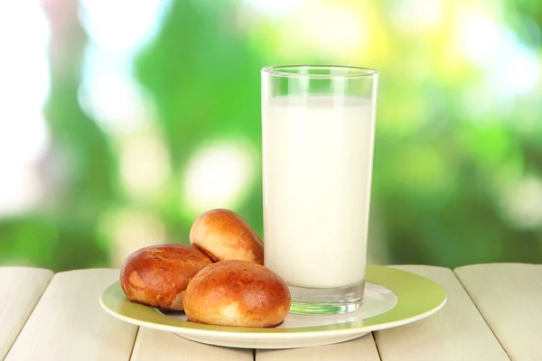 Bread roll and glass of milk on wooden table on nature background — Stock Photo, Image