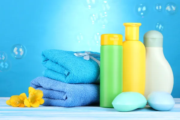 Baby cosmetics, towels and soap on wooden table, on blue background — Stock Photo, Image