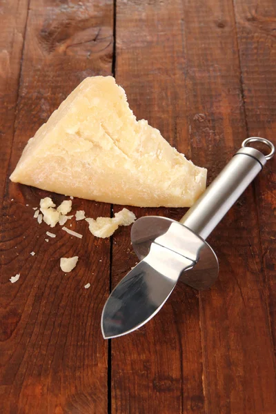 木製のテーブルのクローズ アップにナイフとパルメザン チーズの部分 — ストック写真