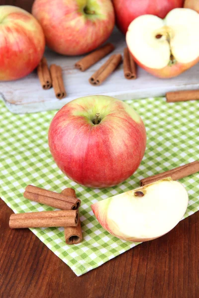 Pommes mûres avec bâtonnets de cannelle sur fond en bois de couleur — Photo