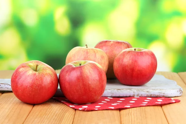Dojrzałe jabłka na drewnianym stole, na jasnym tle — Zdjęcie stockowe