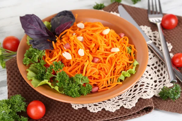 Морковный салат на тарелке на салфетке на деревянном столе — стоковое фото