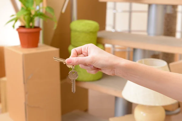 Ženské ruky klíče ob zásobníkem kartonů pozadí: pohyblivé koncept domu — Stock fotografie