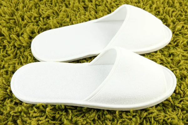 Bílé pantofle na koberec pozadí — Stock fotografie