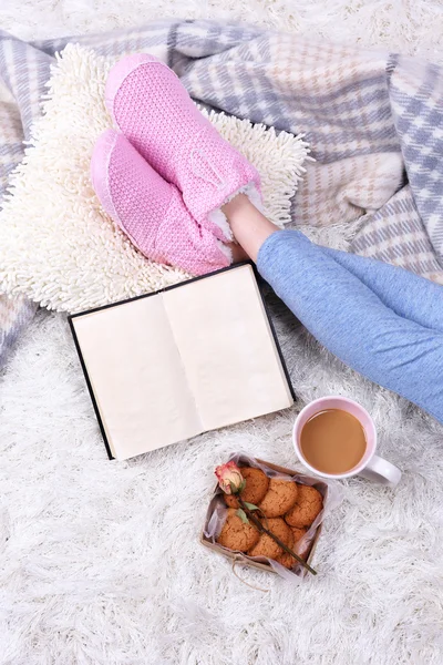 Composición con cuadros calientes, libro, taza de bebida caliente y piernas femeninas, sobre fondo de alfombra de color — Foto de Stock