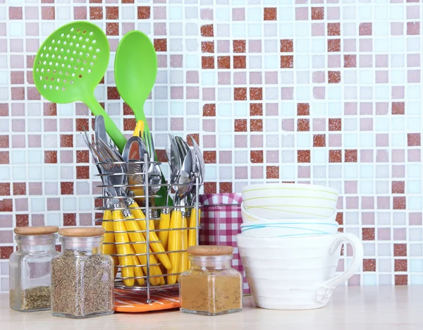 Nádobí a příbory v kuchyni na stole na pozadí dlaždice mozaika — Stock fotografie