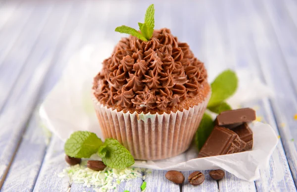 Sabroso cupcake con crema de mantequilla, sobre tabla de madera de color, sobre fondo de luces — Foto de Stock