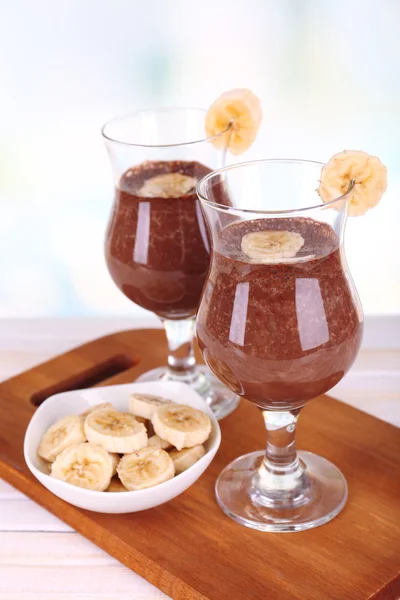 Coquetéis com banana e chocolate na mesa em fundo claro — Fotografia de Stock