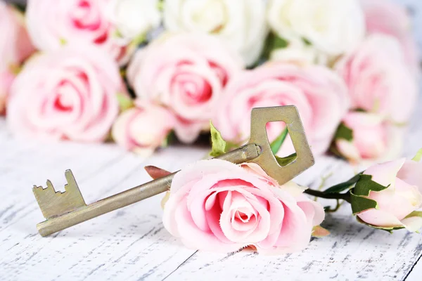 Klíč pro štěstí. konceptuální fotografie. klíč s růží, na světlé dřevěné pozadí — Stock fotografie