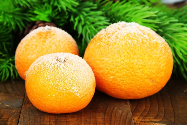 Ripe frosted tangerines with fir branch on wooden background — Stock Photo, Image