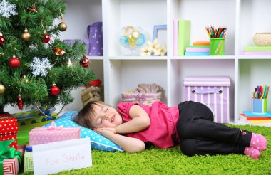 Odada Noel ağacının yakınında uyuyan küçük kız
