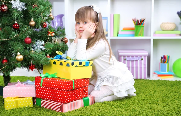 Niña con regalos cerca del árbol de Navidad en la habitación —  Fotos de Stock