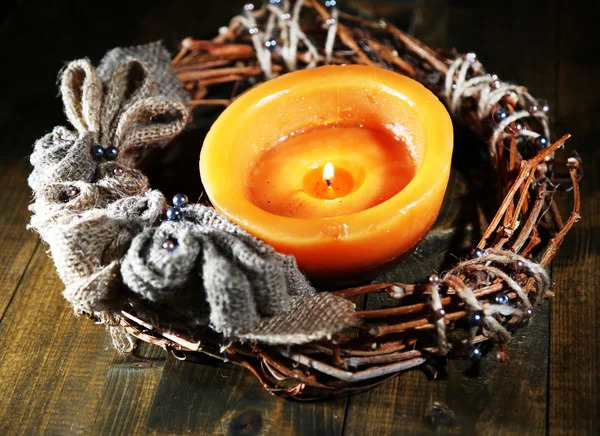 Burning candle with Christmas wreath on wooden background — Stock Photo, Image