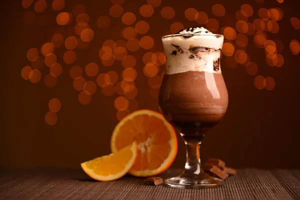 Finom desszert, csokoládé, krém és narancs mártással, asztalon, a háttér világítás — Stock Fotó
