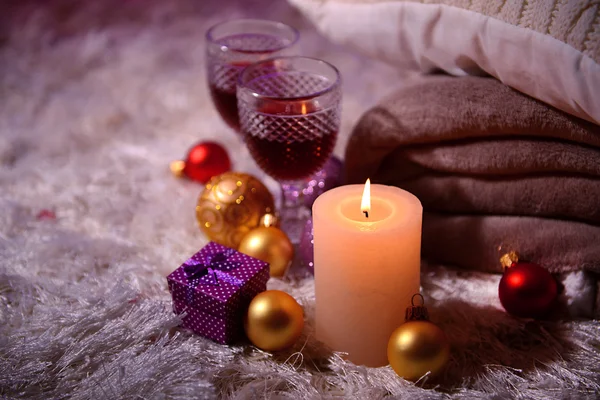 Композиція з пледами, свічками та різдвяними прикрасами, на білому килимі на яскравому фоні — стокове фото
